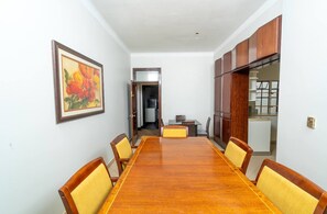 A conference room with a long wooden table, yellow cushioned chairs, a framed painting, and wooden cabinets.