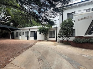 Un edificio con un letrero que dice 'ROSARIO'S' y un patio empedrado con un camino de ladrillos.