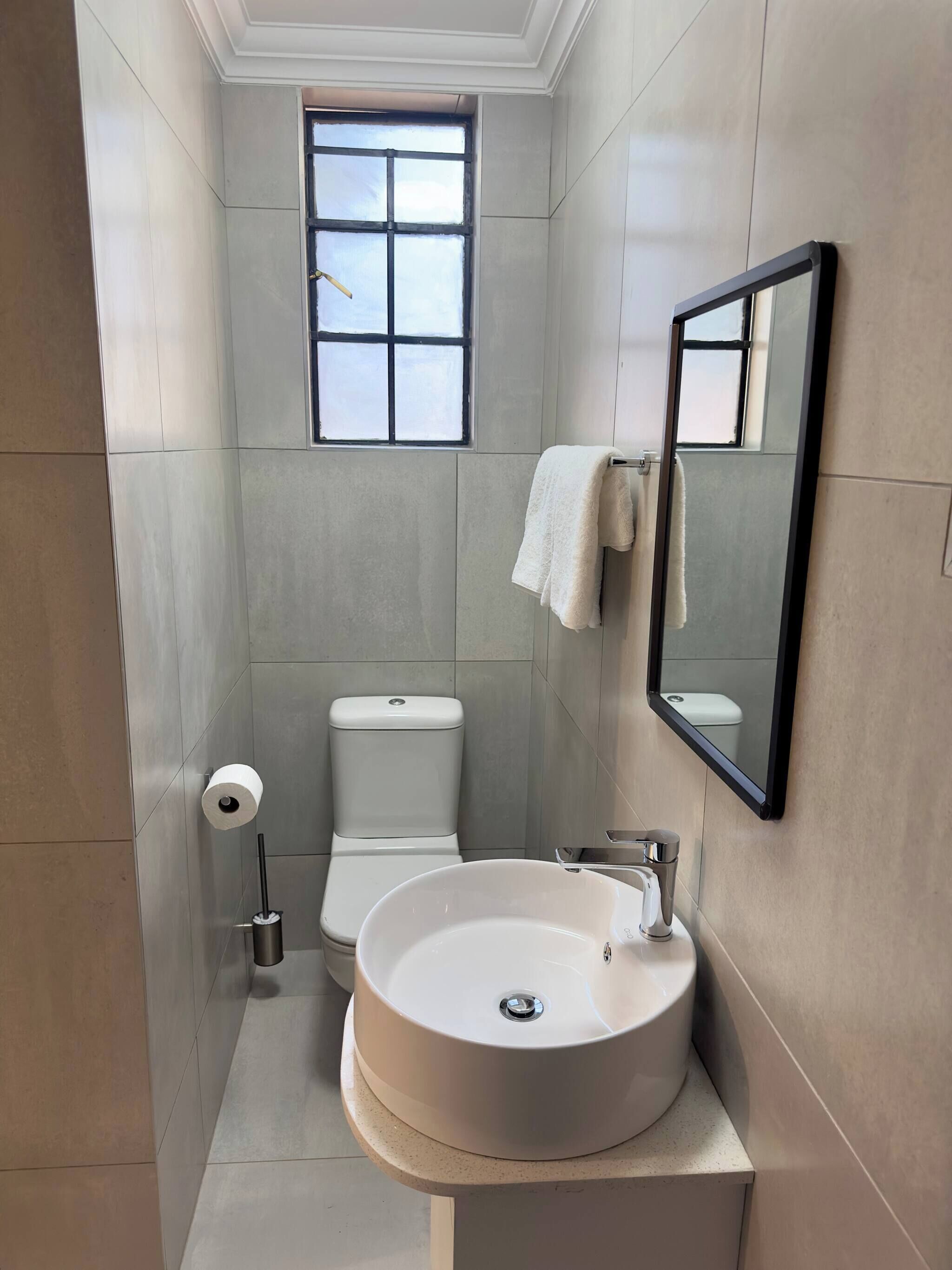 A bathroom with a toilet, sink, and a window.