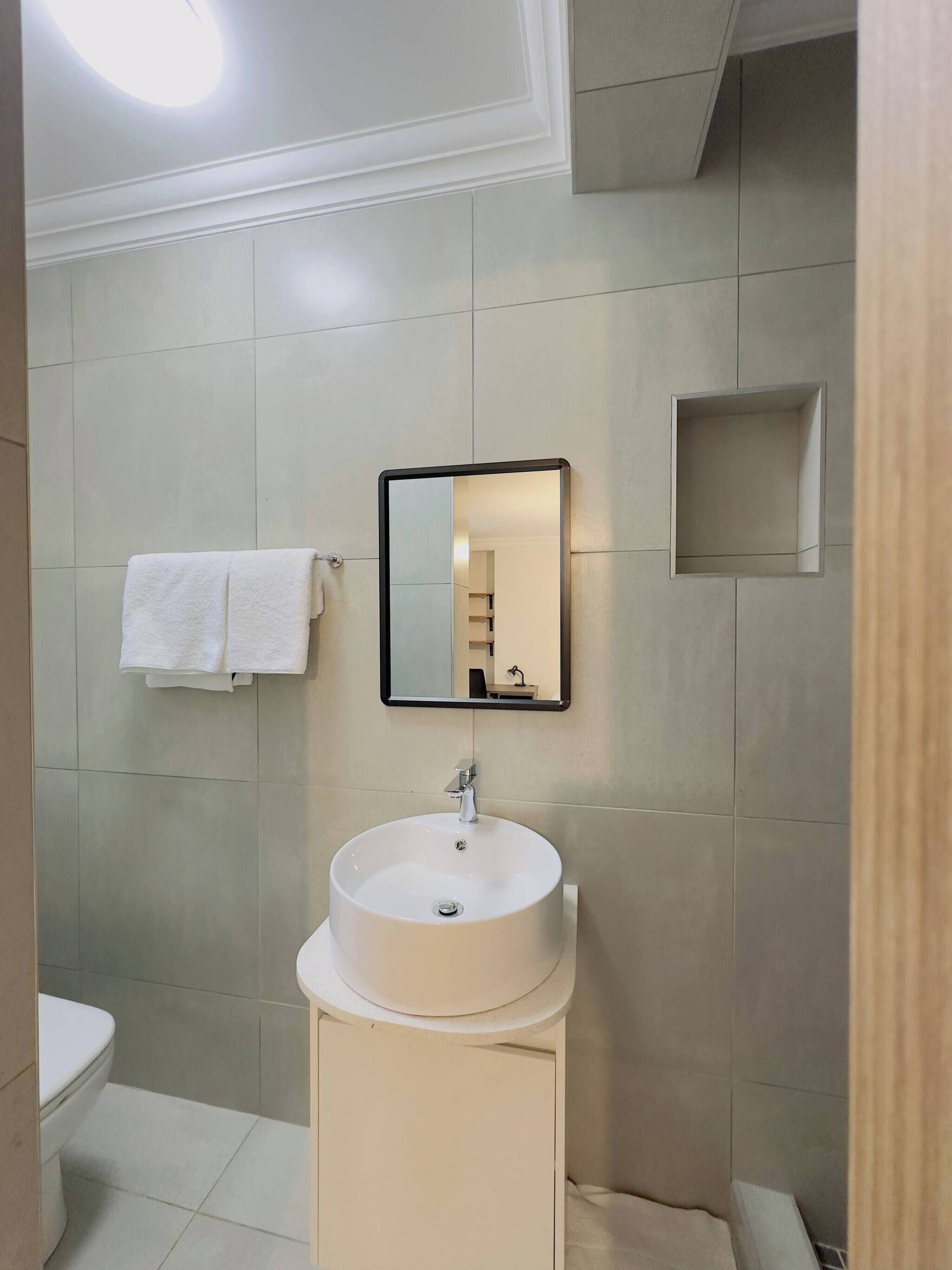 Une salle de bain avec un lavabo blanc, un miroir et un porte-serviettes.