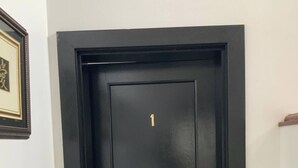 Eine schwarze Tür mit der goldenen Zahl 1 und einem Türknauf.
