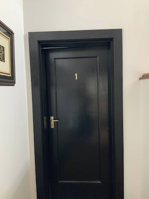 Una puerta negra con el número 1 en dorado y un picaporte.