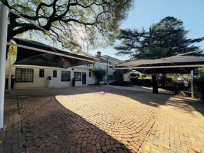 A courtyard with a paved floor, covered seating areas, and a building with windows and doors.