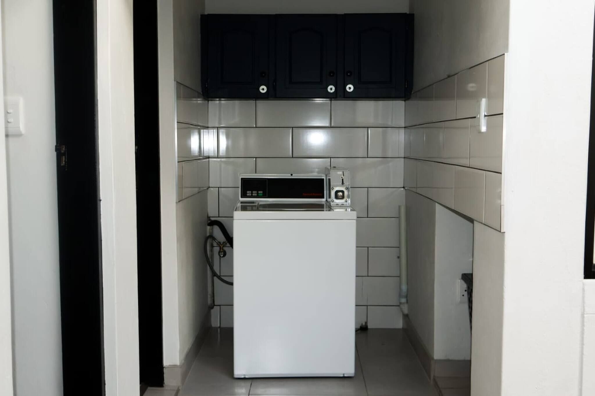Eine kleine Küche mit einem weißen Kühlschrank, einer Mikrowelle und dunklen Schränken.