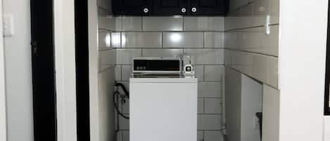 A compact kitchen with a white refrigerator, a microwave, and dark cabinets.