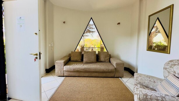 Una habitación con un sofá, un tapete estampado, una puerta y una ventana con vista a árboles.