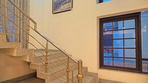 A staircase with a metal railing and granite steps, leading to a landing with a framed picture on the wall. - Collection O NIT Srinagar (Srinagar)