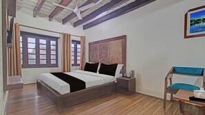 A bedroom with a wooden bed, a nightstand, a chair, and a painting on the wall. - Collection O NIT Srinagar (Srinagar)