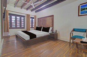 A bedroom with a wooden bed, a nightstand, a chair, and a painting on the wall. - Collection O NIT Srinagar (Srinagar)