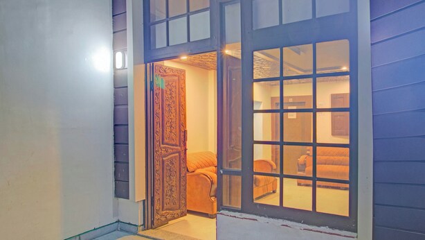 A hallway with a wooden door leading to a room with a bed and a window. - Collection O NIT Srinagar (Srinagar)