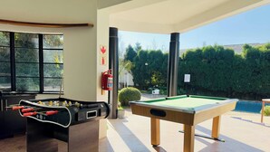 A pool table and foosball table in a well-lit room with large windows. - Room-single Room With Shared Bathroom 1 (Johannesburg)