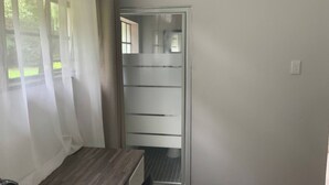 Una habitación con un escritorio de madera, una puerta corredera con paneles de vidrio esmerilado y vistas a la vegetación exterior.