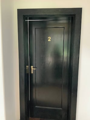 Una puerta negra con el número 2 en dorado y un picaporte.