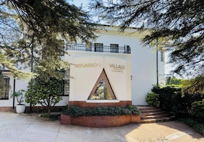 Un edificio con fachada blanca, una ventana triangular y el texto 'ROSARIO'S VILLAGE'.