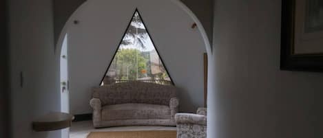 Una habitación con sofá, una mesita y vista a través de un ventanal de arco.