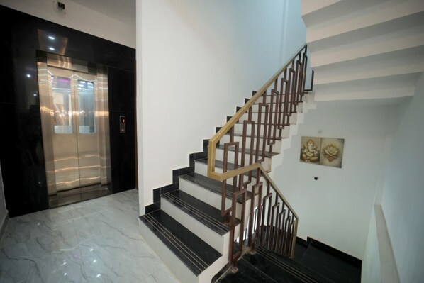 A modern interior with a marble staircase and an elevator. - Amrit Sunshine (Ayodhya)