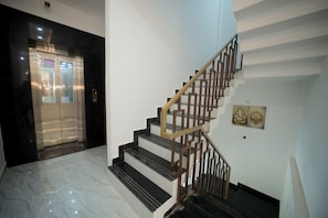 Un interior moderno con una escalera de mármol y un ascensor.