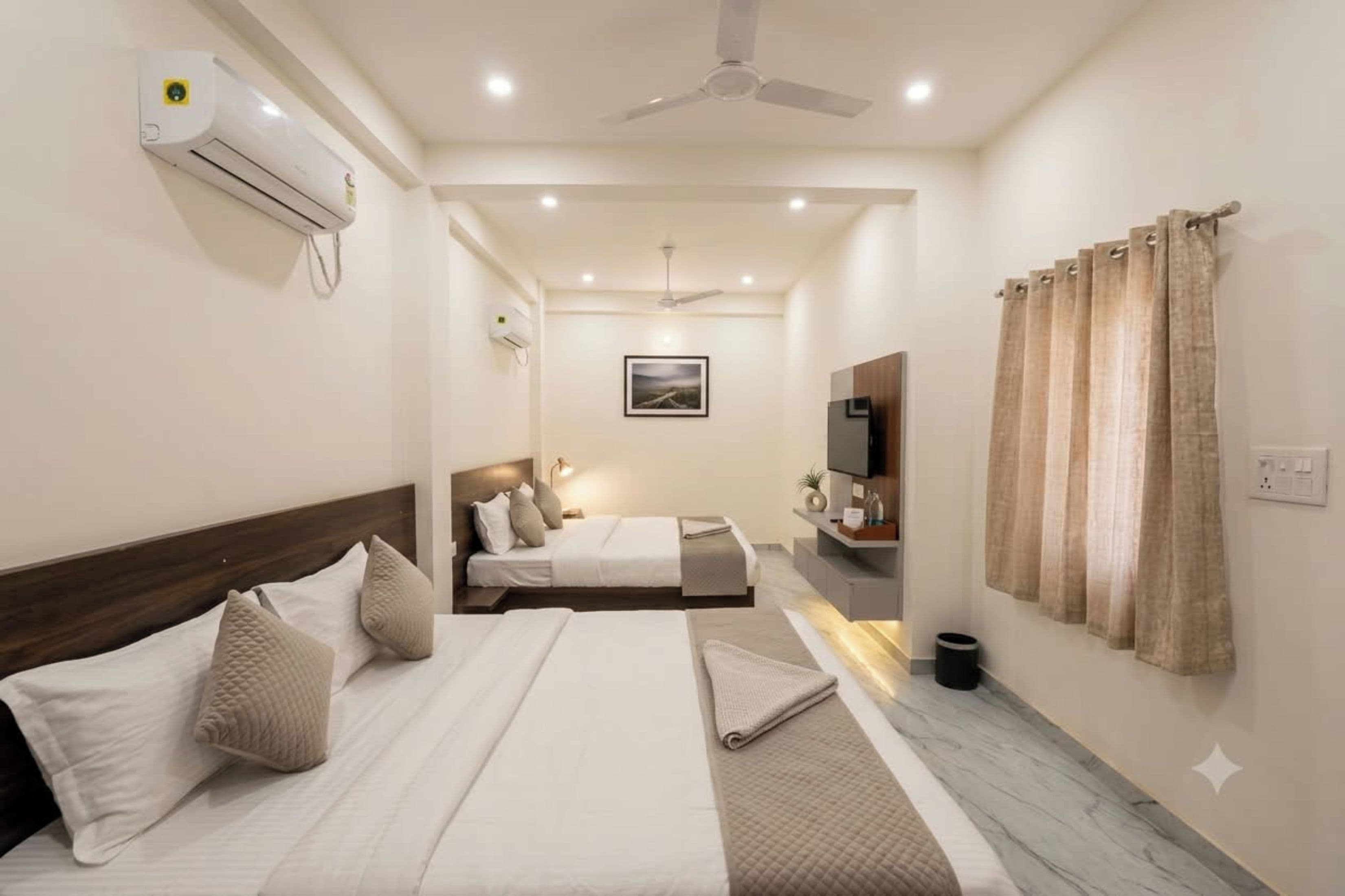 Una habitación de hotel con una cama, un escritorio, una silla, un televisor y un ventanal con cortinas.