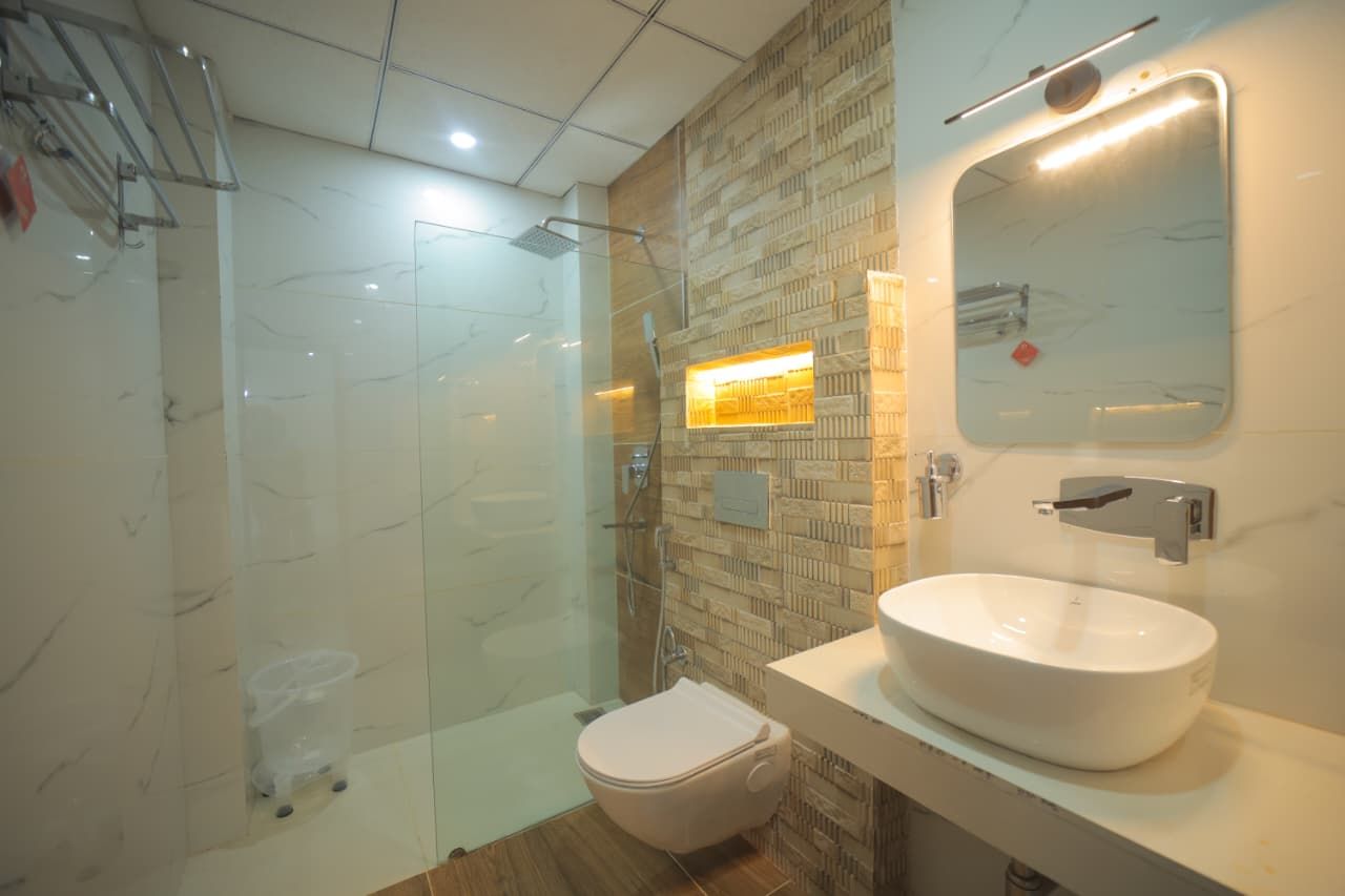 Un baño moderno con ducha envuelta en vidrio, un lavamanos blanco y un espejo.