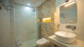 Un baño moderno con ducha envuelta en vidrio, un lavamanos blanco y un espejo.