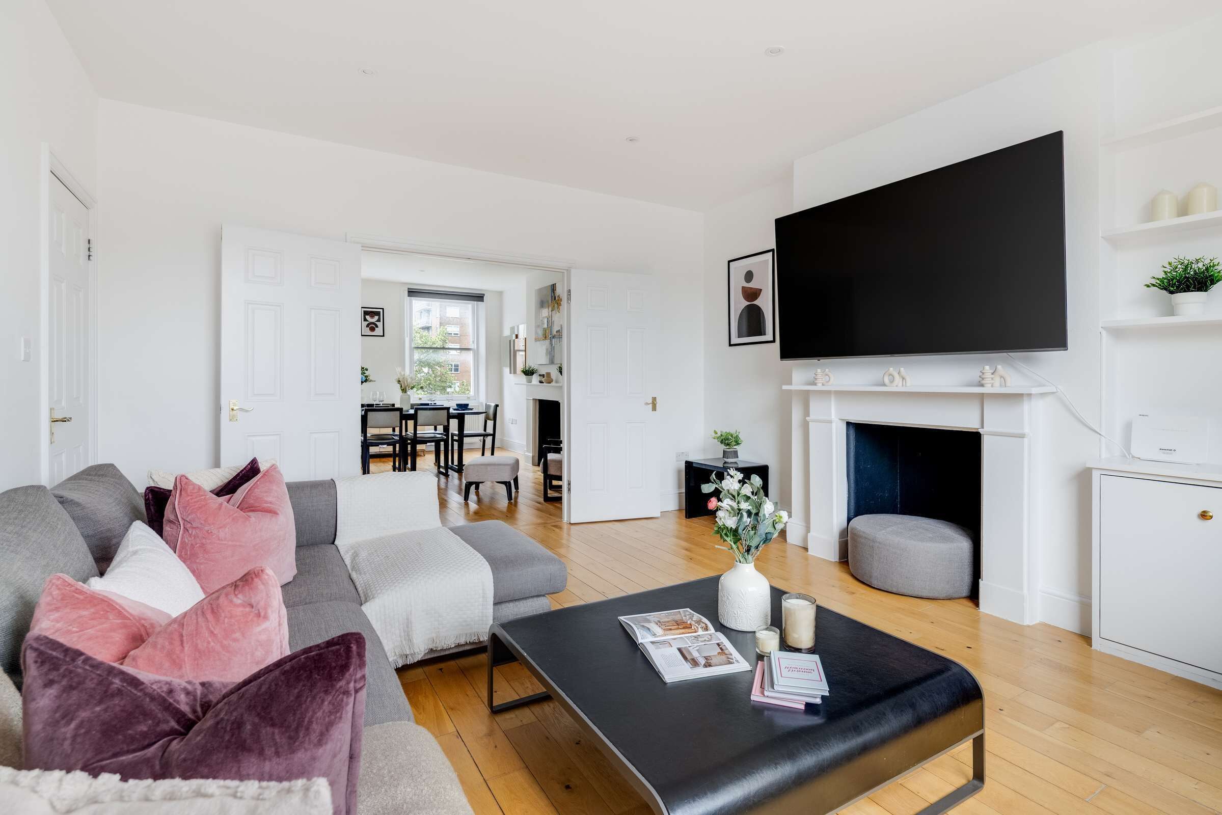 A modern living room with a sofa, coffee table, and a flat-screen TV mounted on the wall.