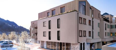 Un bâtiment moderne à plusieurs étages, doté d’un toit plat, de grandes fenêtres et d’une base en pierre.