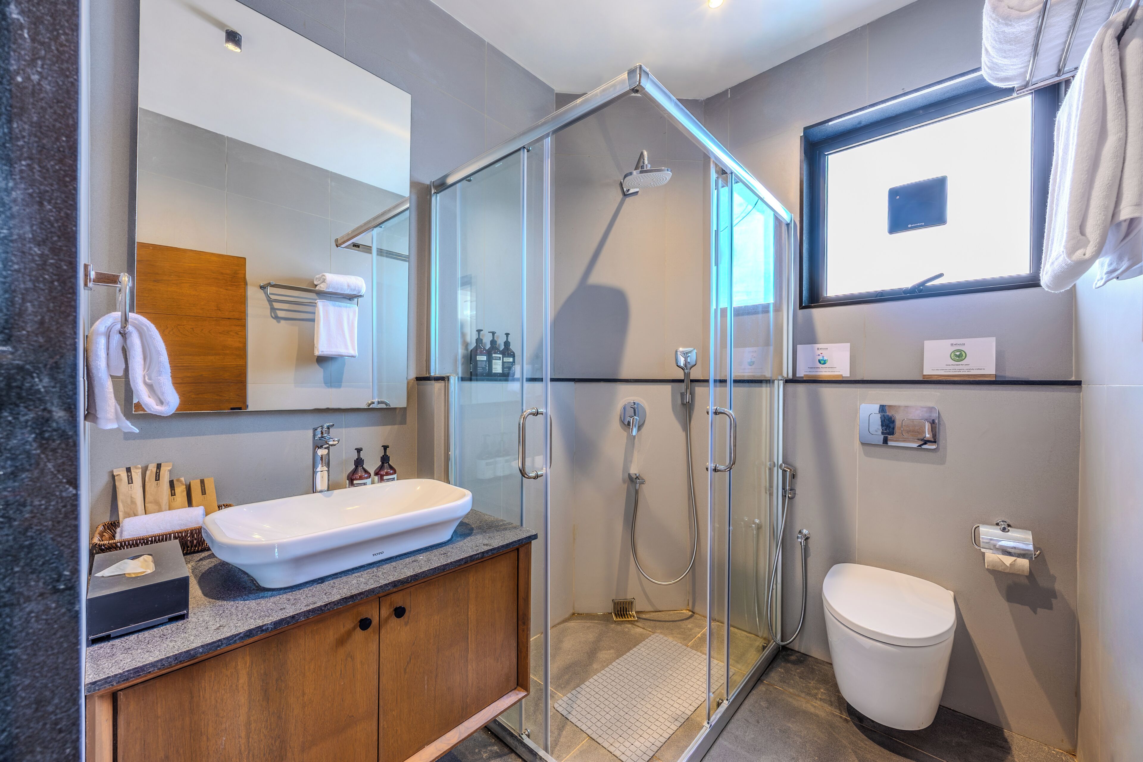 A modern bathroom with a glass-enclosed shower, a white sink, and a toilet.