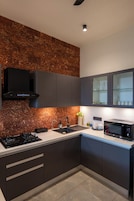 Una cocina moderna con armarios oscuros, campana extractora de acero inoxidable, microondas integrado y salpicadero con textura.