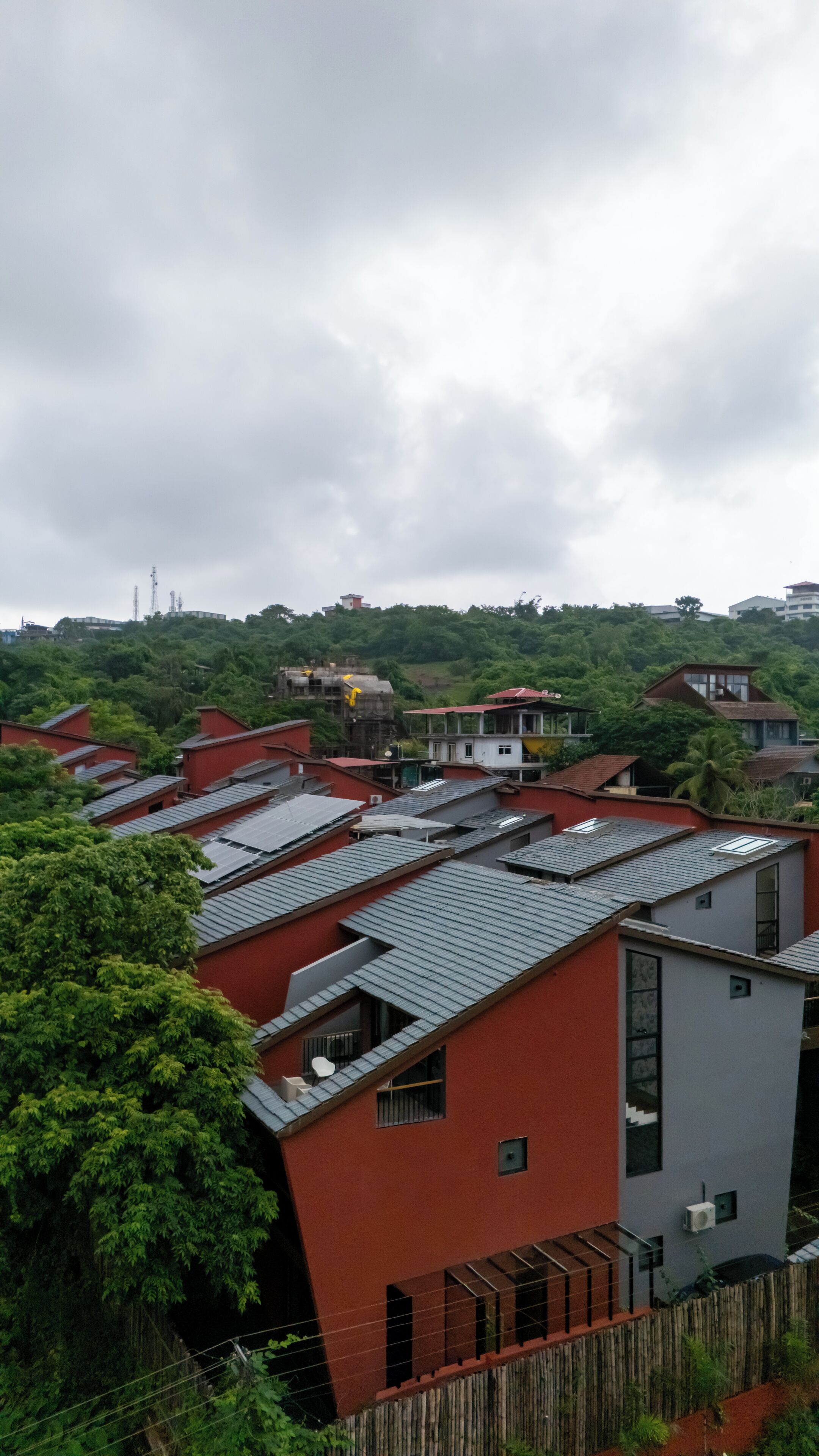 Um bairro residencial com várias casas, algumas com telhados inclinados e outras com telhados planos, cercado por vegetação.