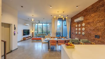A modern living room with a dining area, large windows, and a kitchen.