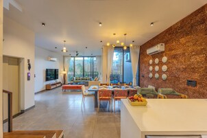 Una sala de estar moderna con comedor, ventanas amplias y una cocina.