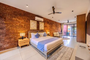 Quarto moderno com uma cama grande, mesas de cabeceira, ventilador de teto e vista para o exterior.
