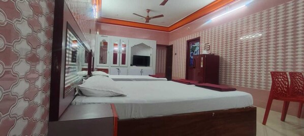 A bedroom with a bed, wardrobe, television, and a red chair.