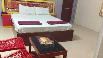 A hotel room with a bed, two red chairs, a small table with a card game, and a door.