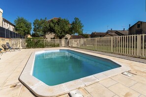A rectangular swimming pool with a white fence surrounding it, set in a residential area with houses and trees in the background. - Spacious Holiday Home for 10 person (Saint-Laurent-la-Vernède)