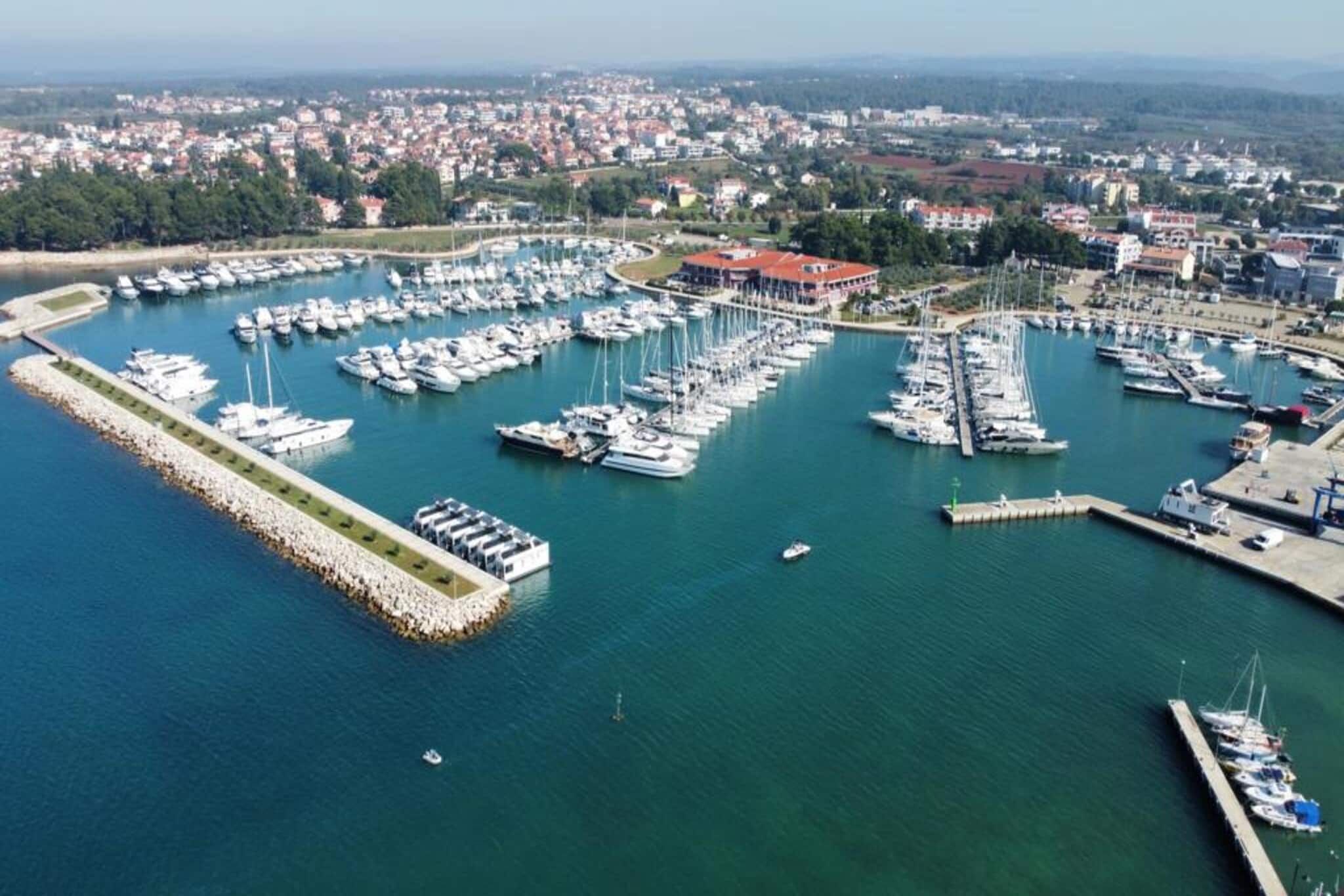 Une vue aérienne d’une marina où sont amarrés de nombreux bateaux, le tout étant entouré d’une ville côtière.