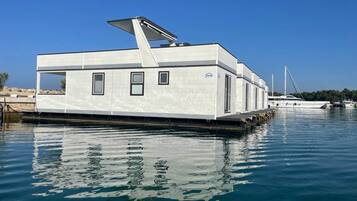 Una casa flotante con techo plano, ventanas y una pequeña zona de cubierta.