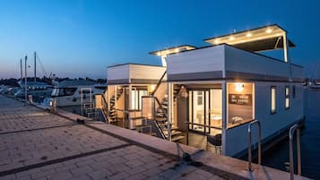 Propiedad frente al mar con diseño moderno, que cuenta con un espacio al aire libre cubierto, una escalera que conduce a la entrada y un cartel que indica que es un albergue marítimo.