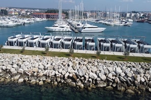 A marina with multiple yachts docked and modern, multi-level buildings with glass facades.