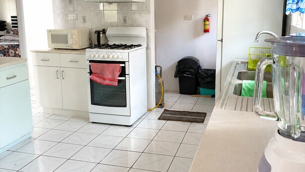 Une cuisine avec des armoires blanches, une cuisinière, un four à micro-ondes et un mixeur sur le plan de travail.