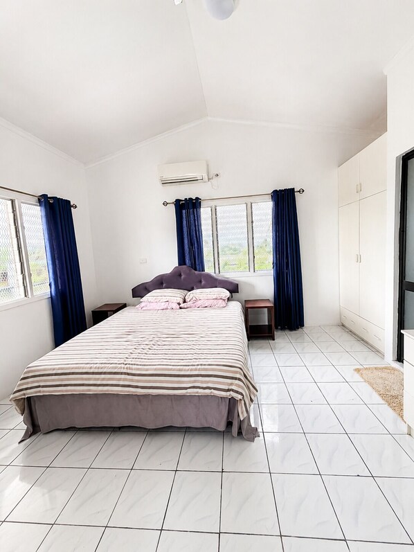 Un dormitorio con cama, ventana, armario y aire acondicionado.