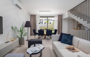 A modern living room with a sofa, a dining table with chairs, a coffee table, a TV, and a staircase. - Beautiful home in Tkon (Tkon)