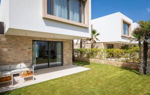 A modern house with a stone facade, large sliding glass doors, a flat roof, and a well-maintained lawn. - Luxurious home in Tkon (Tkon)