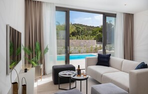Ein modernes Wohnzimmer mit einer Couch, einem Couchtisch und Blick auf einen Swimmingpool.
