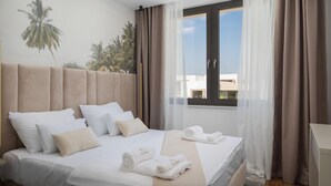 A hotel room with a bed, pillows, a window with curtains, and a wall mural. - Beautiful home in Tkon (Tkon)