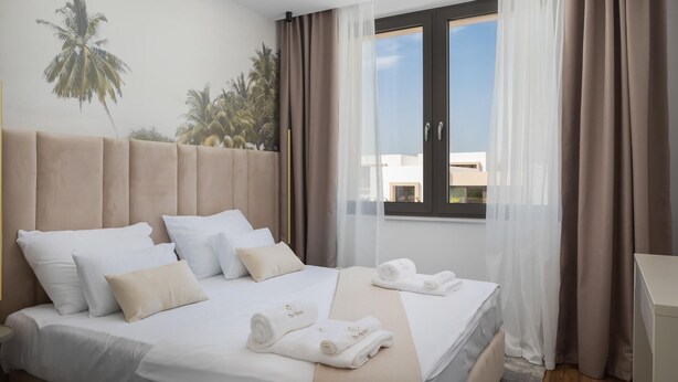 A hotel room with a bed, pillows, a window with curtains, and a wall mural. - Stunning home in Tkon (Tkon)