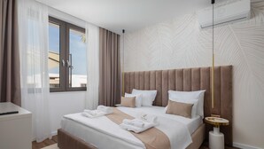 Une chambre d’hôtel moderne avec un grand lit, une table de chevet, une lampe et une vue sur l’extérieur.