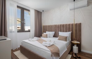 A modern hotel room with a large bed, a bedside table, a lamp, and a view of the outside. - Beautiful home in Tkon (Tkon)