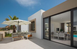 A modern outdoor living space with a sofa, coffee table, and umbrella, and a dining area with chairs and a table. - Beautiful home in Tkon (Tkon)