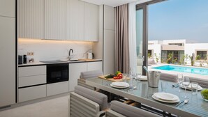 Une cuisine moderne avec un coin repas, une vue sur la piscine et un four encastré.